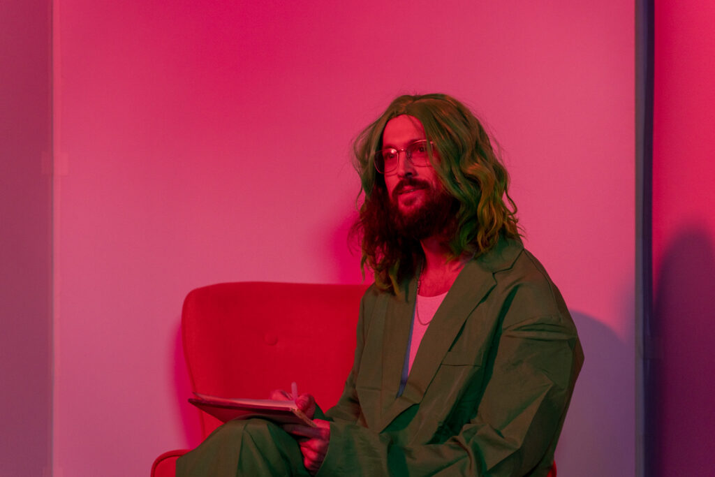 man with green wig and green suit, seeming to anticipate something